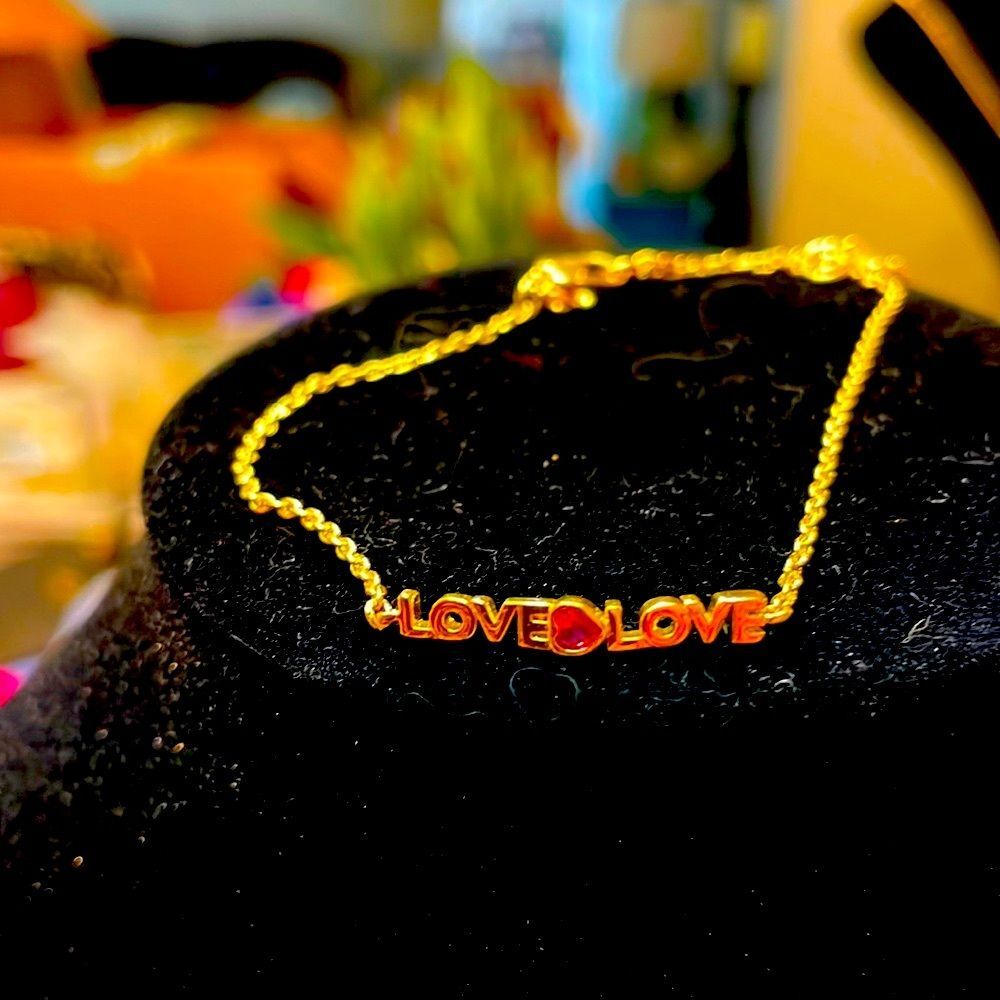 Very cute Kate Spade bracelet that says love twice with a pink stone in middle.